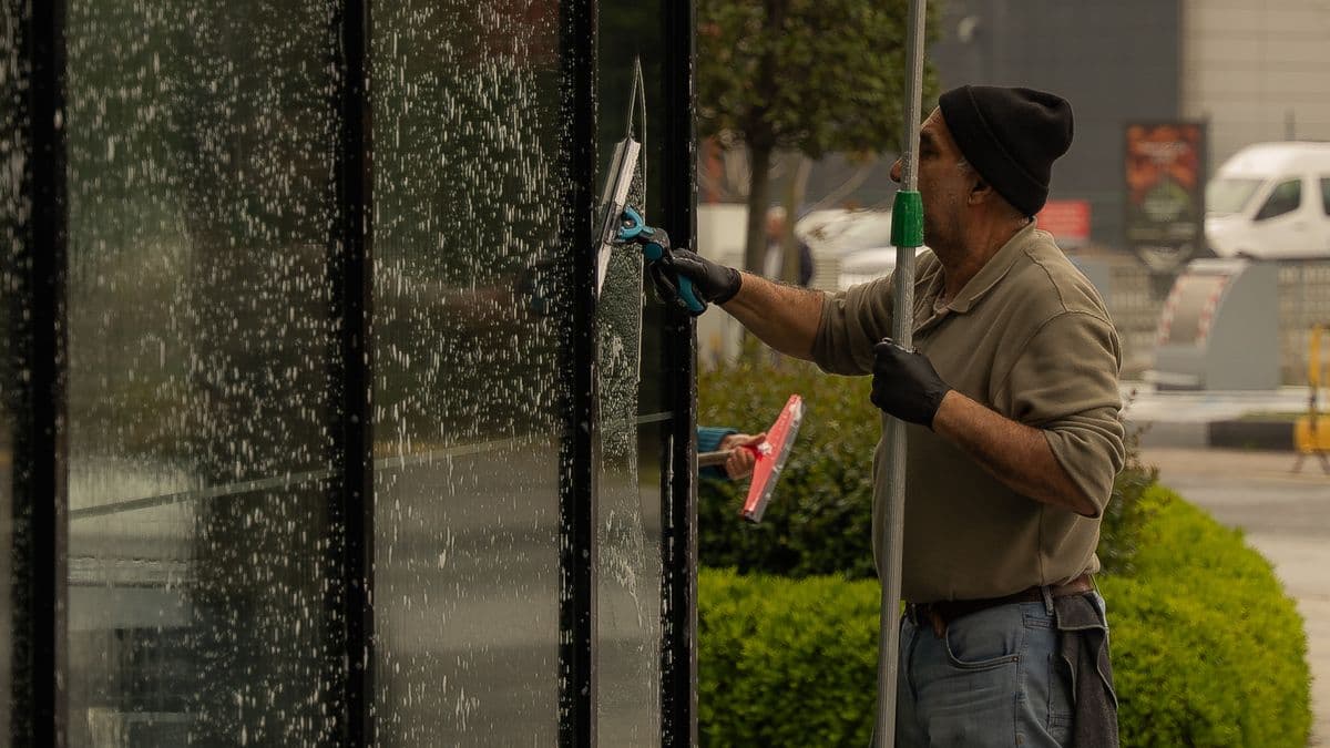 A window cleaner using a squeegee to clean a glass storefront window.